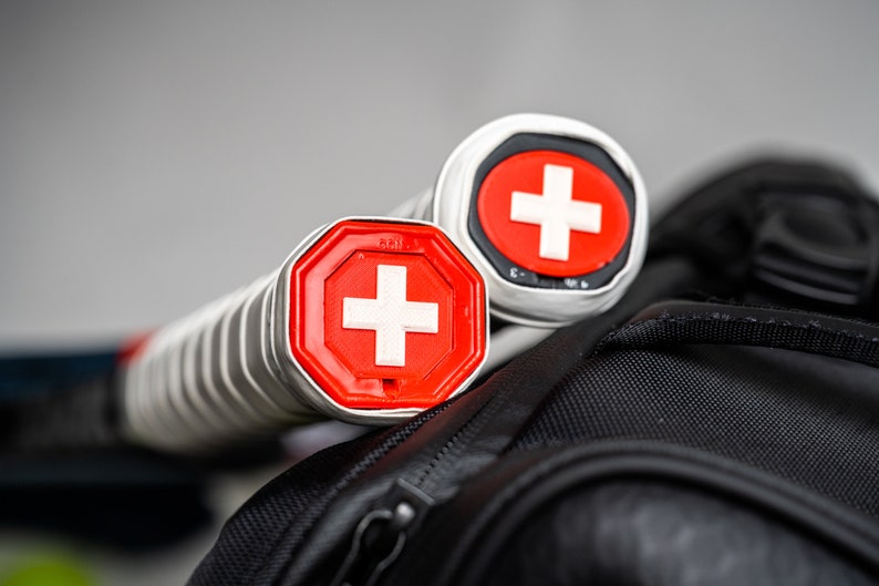 May include: Two silver tennis rackets with red and white Swiss cross logos on the handles.