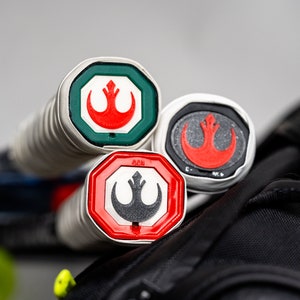 May include: Three tennis rackets with red, white, and green Rebel Alliance logos on the ends of the handles.