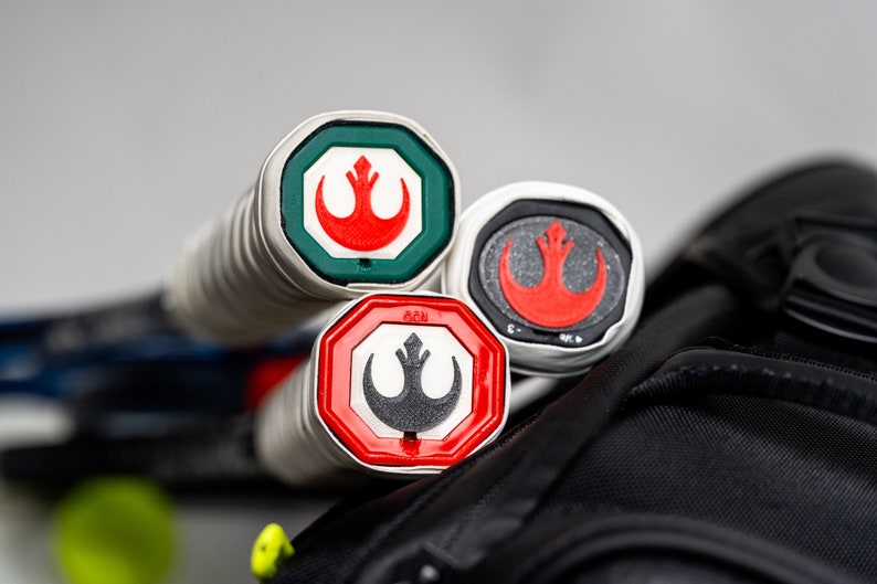 May include: Three tennis rackets with red, white, and green Rebel Alliance logos on the ends of the handles.