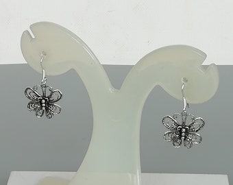 May include: A pair of silver butterfly earrings with intricate filigree designs.