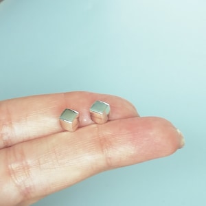 Op de afbeelding: Een paar zilveren kubus oorbelletjes. De oorbelletjes zijn klein en simpel, en zouden een geweldige aanvulling zijn op elke sieradencollectie.