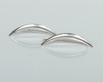 May include: A pair of silver ear cuffs in the shape of a crescent moon. The cuffs are made of smooth, polished metal and have a simple, modern design.