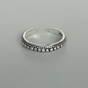 May include: A silver toe ring with a beaded design.
