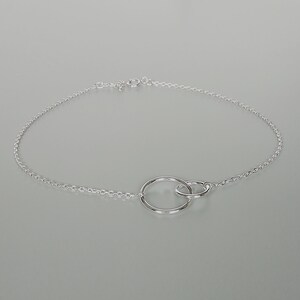 May include: A silver chain bracelet with two interlocking circles as the centerpiece.
