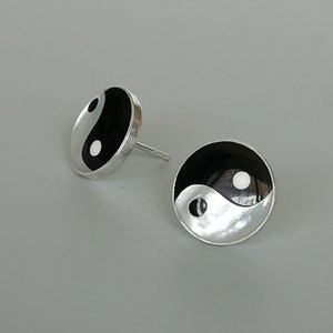 Op de afbeelding: Een paar zilveren oorbellen met een zwart-wit yin yang symbool ontwerp.