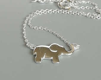 May include: A silver chain necklace with a silver elephant pendant. The elephant is facing right and has its trunk raised.