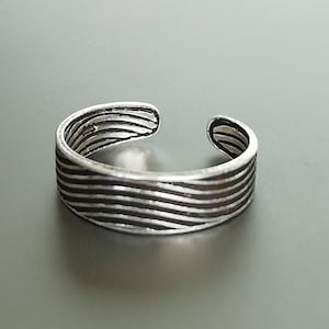 Può includere: Anello per dita dei piedi in argento con un design ondulato e a righe.