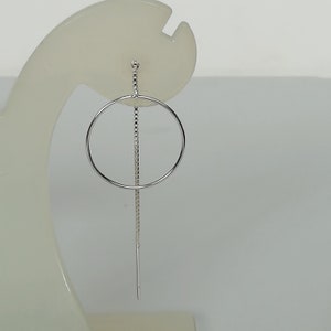 Puede incluir: Pendientes de aro de plata con un círculo y una cadena larga.