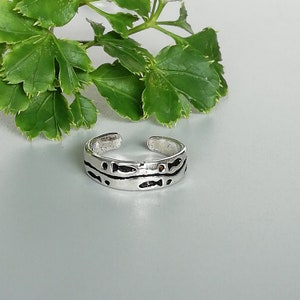 Peut inclure: Bague d'orteil en argent avec un motif de poissons sur la bande.