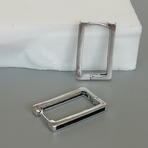 Op de afbeelding: Een paar zilveren creolen. Een oorring heeft een zwarte lijn langs de rand van de cirkel.