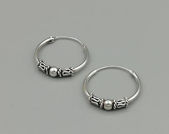 May include: A pair of silver hoop earrings with a small bead and decorative accents.