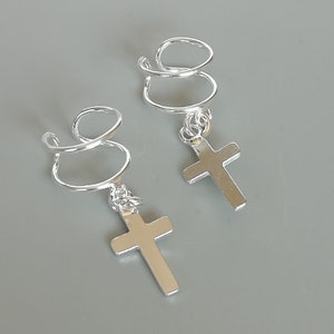 May include: Two silver hair clips with a cross charm. Each clip is a spiral design.