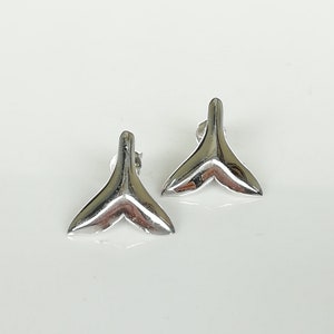 May include: A pair of silver fishtail earrings. The earrings are small and delicate, and they would make a great gift for someone who loves the ocean.