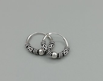 May include: A pair of silver hoop earrings with a textured design and a small bead accent.