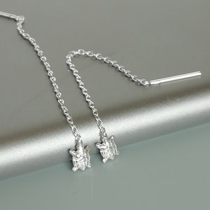 May include: A pair of silver dangle earrings with a turtle charm at the end of each chain.