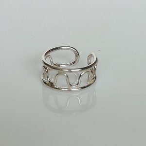 May include: Silver ear cuff with a wavy design. The cuff is open and adjustable to fit most ear sizes.