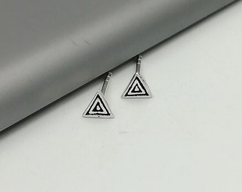 May include: A pair of silver triangle stud earrings with a black geometric design.