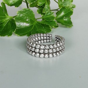 May include: A silver ring made of three rows of small, round beads.