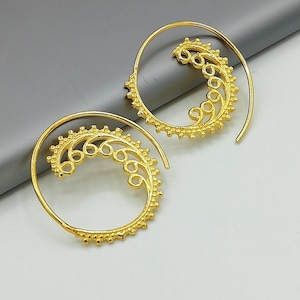 Könnte beinhalten: Ein Paar goldfarbene Creolen mit einem Spiraldesign. Die Ohrringe sind aus Metall und haben ein zartes, filigranes Muster.