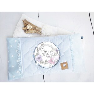 Op de afbeelding: Een lichtblauw kussen met witte stippen en een witte kantversiering. Het kussen heeft een ronde applicatie met een fee en de tekst "Steffi's Stick Stuff".