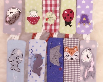 May include: Set of ten fabric strips with embroidered designs. The strips are in various colors and patterns, including polka dots, gingham, and hearts. Each strip features a different embroidered animal or design, such as a mouse, a strawberry, a ladybug, a fox, and a fish.
