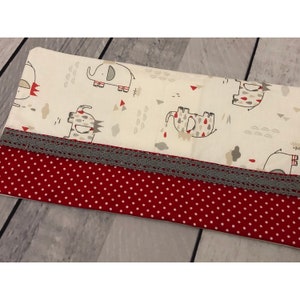 May include: A white pillowcase with a red and grey polka dot pattern on the bottom. The top of the pillowcase features a white background with a grey and red elephant design.