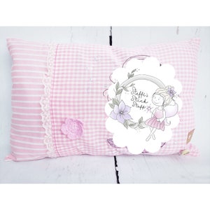 Op de afbeelding: Roze en wit gestreept kussen met een ruitjespatroon en een witte cirkel met een fee-illustratie en de tekst "Steffi's Stick Staff".