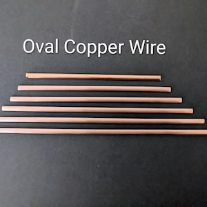 May include: Six straight segments of oval copper wire arranged horizontally in order of increasing length. The metallic copper pieces have a smooth, reflective finish. The text "Oval Copper Wire" is printed in white above the wire segments.
