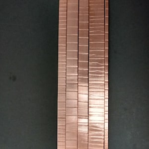 May include: Five copper-coloured metal strips with a textured surface.