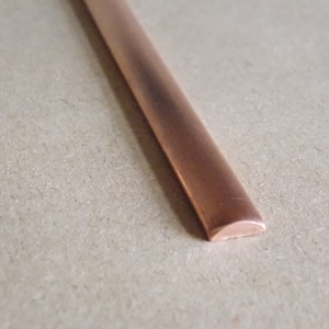 May include: A copper strip with a rounded edge. The strip is flat and has a smooth, polished surface.