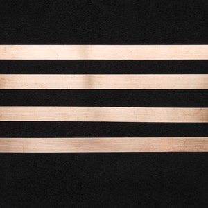 May include: Four horizontal strips of copper tape on a black background.