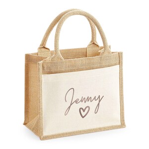 A beige tote bag with a printed name and heart design on it.