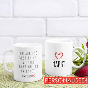 Op de afbeelding: Twee witte keramische mokken. Eén mok bevat de zwarte tekst: YOU ARE THE BEST THING I'VE EVER FOUND ON THE INTERNET - LOVE ISOBEL met een klein rood hartje. De andere mok toont een rood hartpictogram boven de zwarte tekst: HARRY.