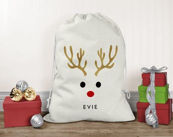 May include: A white drawstring gift sack featuring a gold reindeer antler graphic, two black circular eyes, a red circular nose, and the name EVIE printed in black capital letters centered below the reindeer face design.