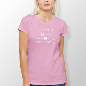 A woman wearing a pink t-shirt with the text "Maid of Honor Charlotte" printed on it.