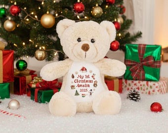May include: A beige plush teddy bear with a white patch on its chest featuring the text My 1st Christmas Amelia 2025, surrounded by small colorful illustrations of a Santa hat, pinecone, stocking, teddy bear, Christmas tree, snowman, and mug.