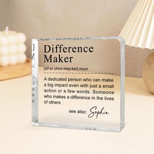a clear glass block with a definition of a " Difference Maker" written on it.