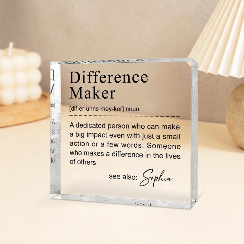 a clear glass block with a definition of a " Difference Maker" written on it.