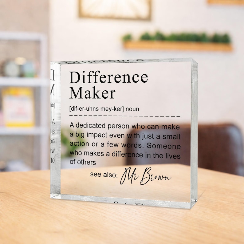 A clear glass block with the definition of a " Difference Maker" written on it, along with a quote attributed to Mr. Brown.