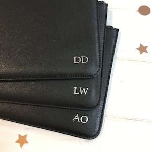 May include: Three black leather pouches with silver initials, "DD", "LW", and "AO", are stacked on top of each other.
