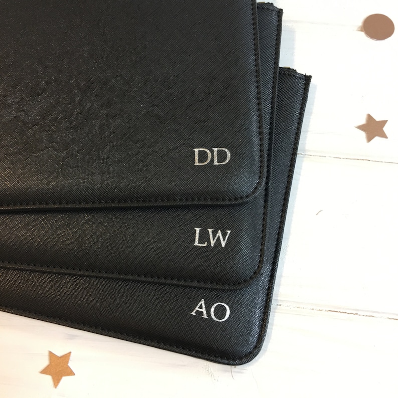 May include: Three black leather pouches with silver initials, "DD", "LW", and "AO", are stacked on top of each other.