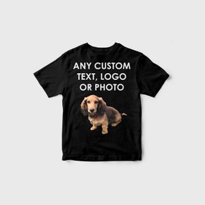 Puede incluir: Camiseta negra con el texto "ANY CUSTOM TEXT, LOGO OR PHOTO" en blanco. Un perro salchicha aparece debajo del texto. El perro tiene pelaje marrón y canela y lleva un collar rojo.