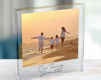 May include: A clear acrylic block photo frame featuring a printed photograph of a family of four walking along a sandy beach at sunset. The text "Our Family June 2022" is printed in black script on the lower portion of the transparent acrylic block.