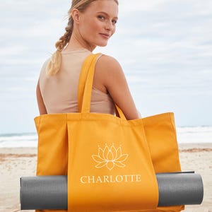 A woman sits on a wooden bench, holding a large orange tote bag with the word "CHARLOTTE" printed on it.