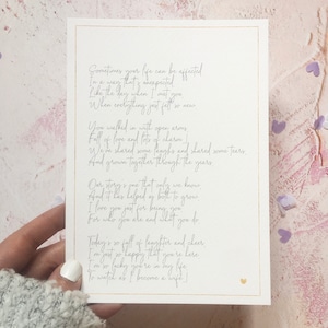 May include: A handwritten poem on a white card with a gold border. The poem is about love and how the writer's life has been affected by the person they are with. The poem ends with the line "To watch as I become a wife!"