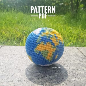 Puede incluir: Un globo terráqueo de ganchillo esférico con océanos azules y masas terrestres amarillas y verdes. El texto PATTERN PDF aparece en la parte superior y el texto LHYARNDESIGN es visible en la parte inferior derecha de la esfera.