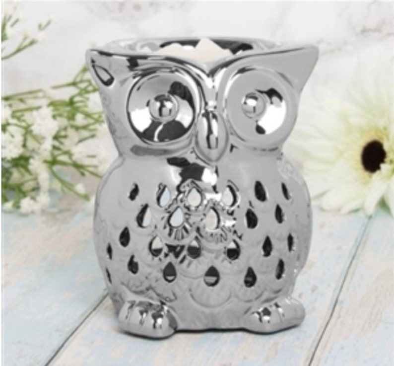 May include: Silver owl shaped ceramic wax warmer with a decorative cut-out design. The warmer has a well in the top for melting wax.