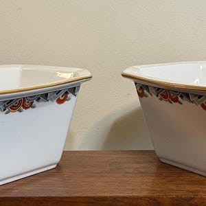 Könnte beinhalten: Zwei rechteckige Schalen aus weißer Keramik mit abgeschrägten Ecken und goldfarbenen Rändern. Der obere äußere Rand ist mit einem geometrischen Muster in Orange, Grau und Schwarz auf der weißen Porzellanoberfläche verziert.