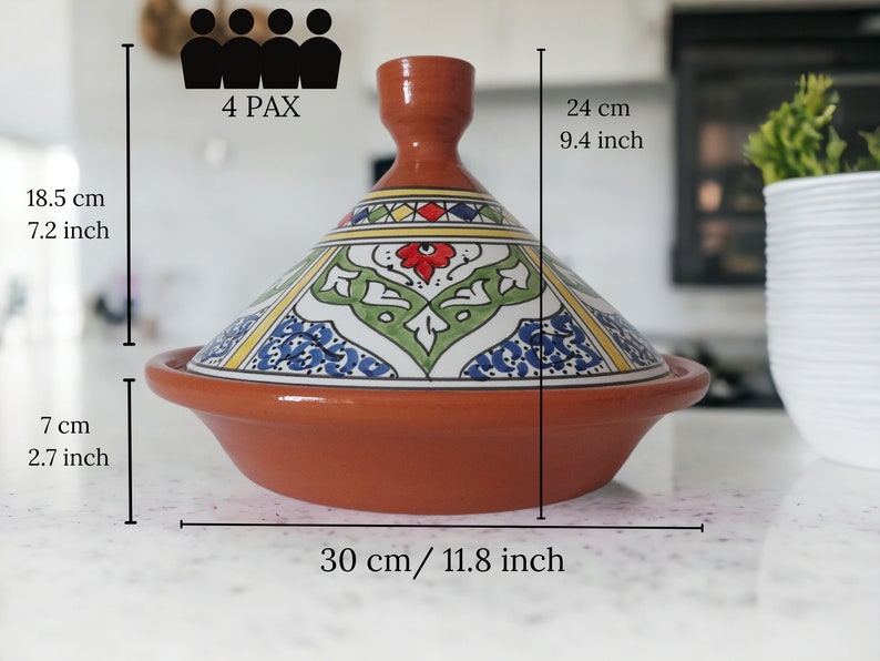 May include: A terracotta tagine with a conical lid featuring hand-painted floral and geometric patterns in red, green, blue, and yellow. The base measures 11.8 inches wide, with a total height of 9.4 inches. It is labeled for 4 PAX capacity.