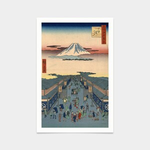May include: A woodblock print depicting Mount Fuji in the distance, with a bustling street scene in the foreground. The print is in shades of blue, green, and brown, with a red and white inscription in the upper right corner.